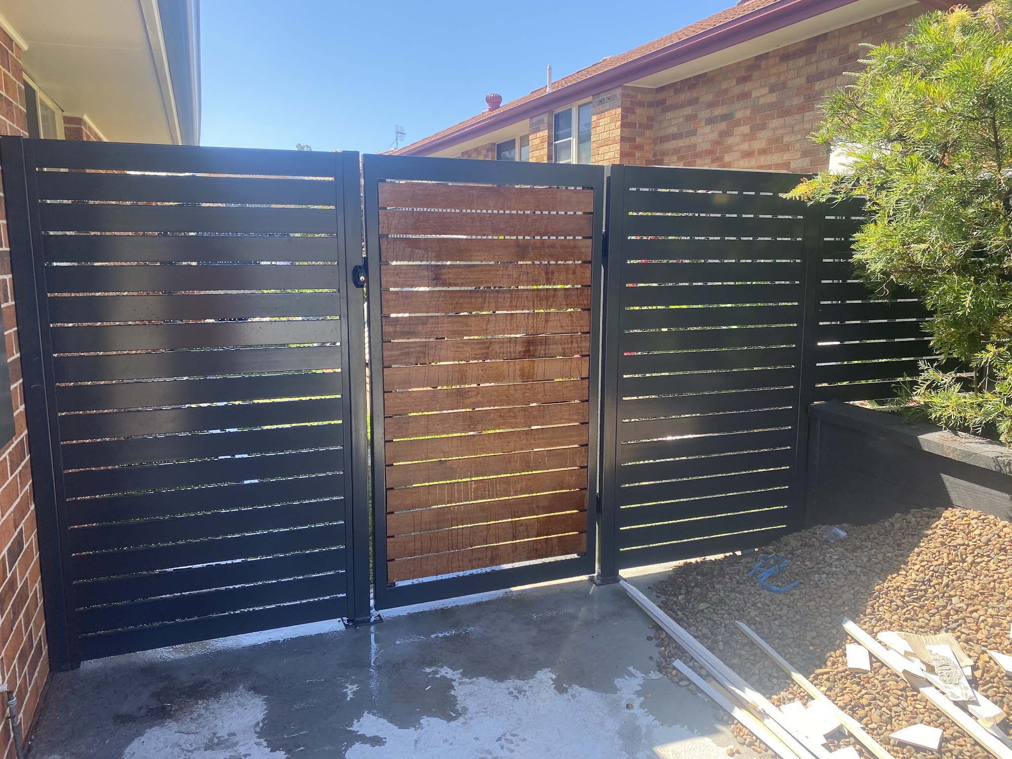 Black aluminium horizontal slat fence and gate with a timber look slat gate panel