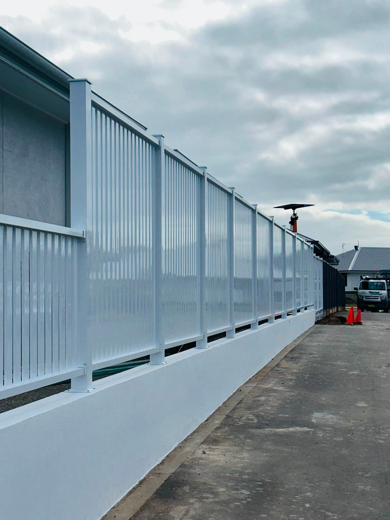 White aluminium batten fence on a rendered plinth